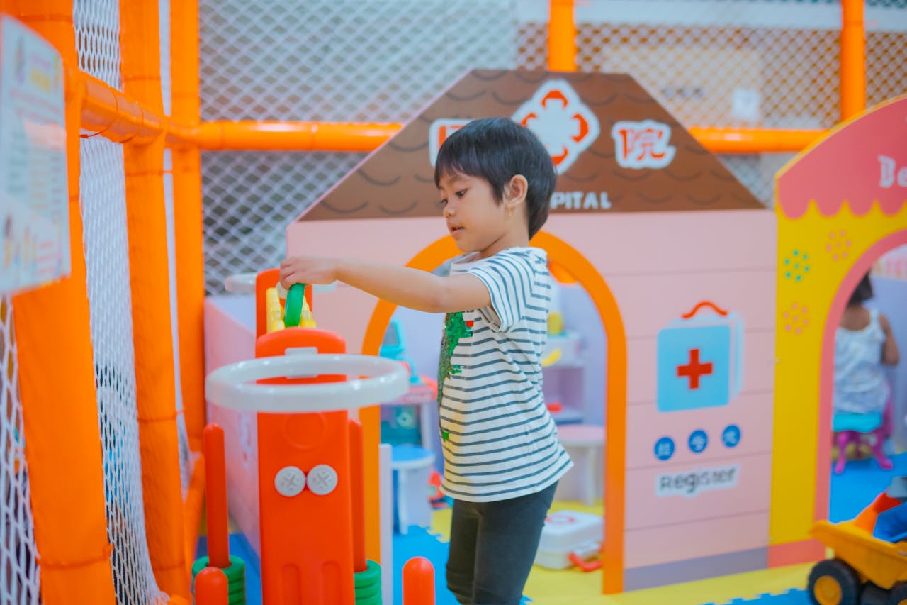 A child enjoys playtime in a colorful indoor playground with toys and structures.