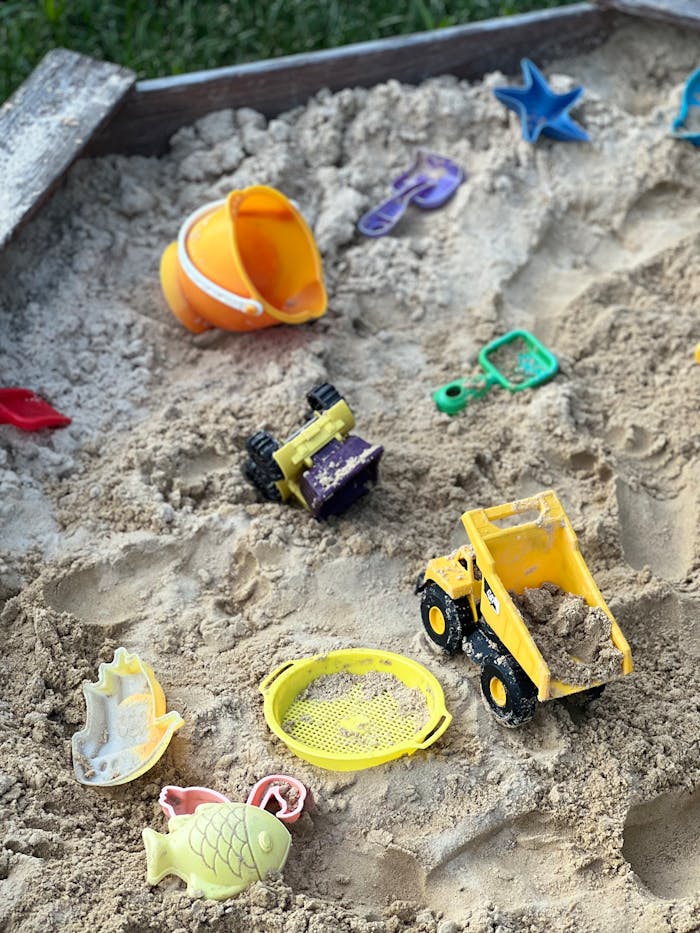Colorful sandbox with toy trucks and sand molds, ideal for kids' play.
