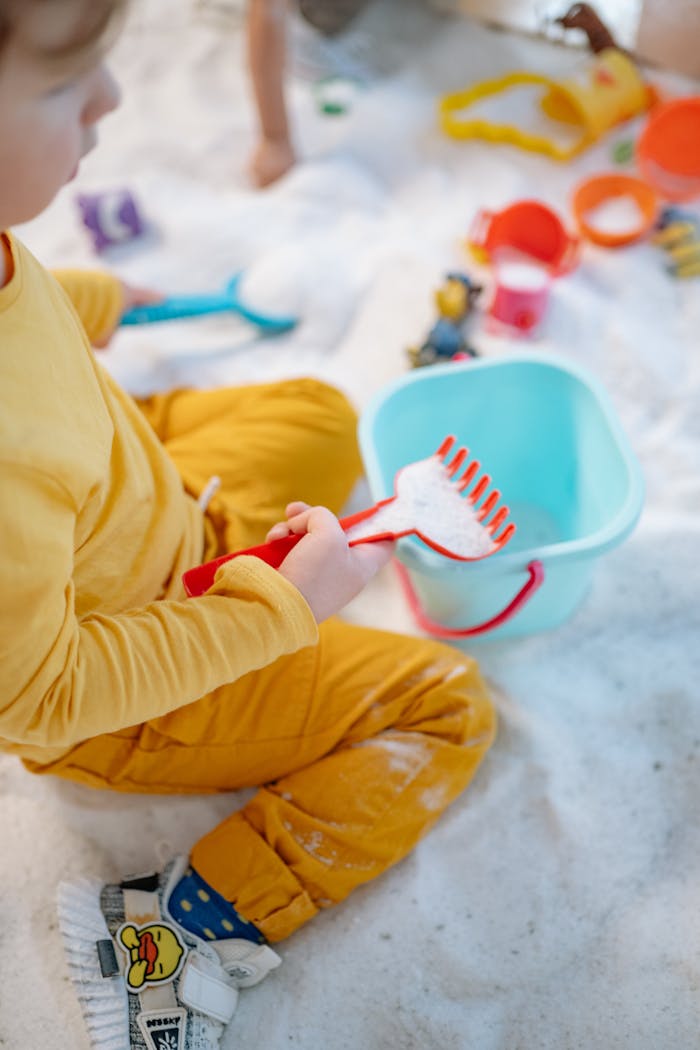 A young child playing with colorful toys and white sand, engaging in mindful activities.